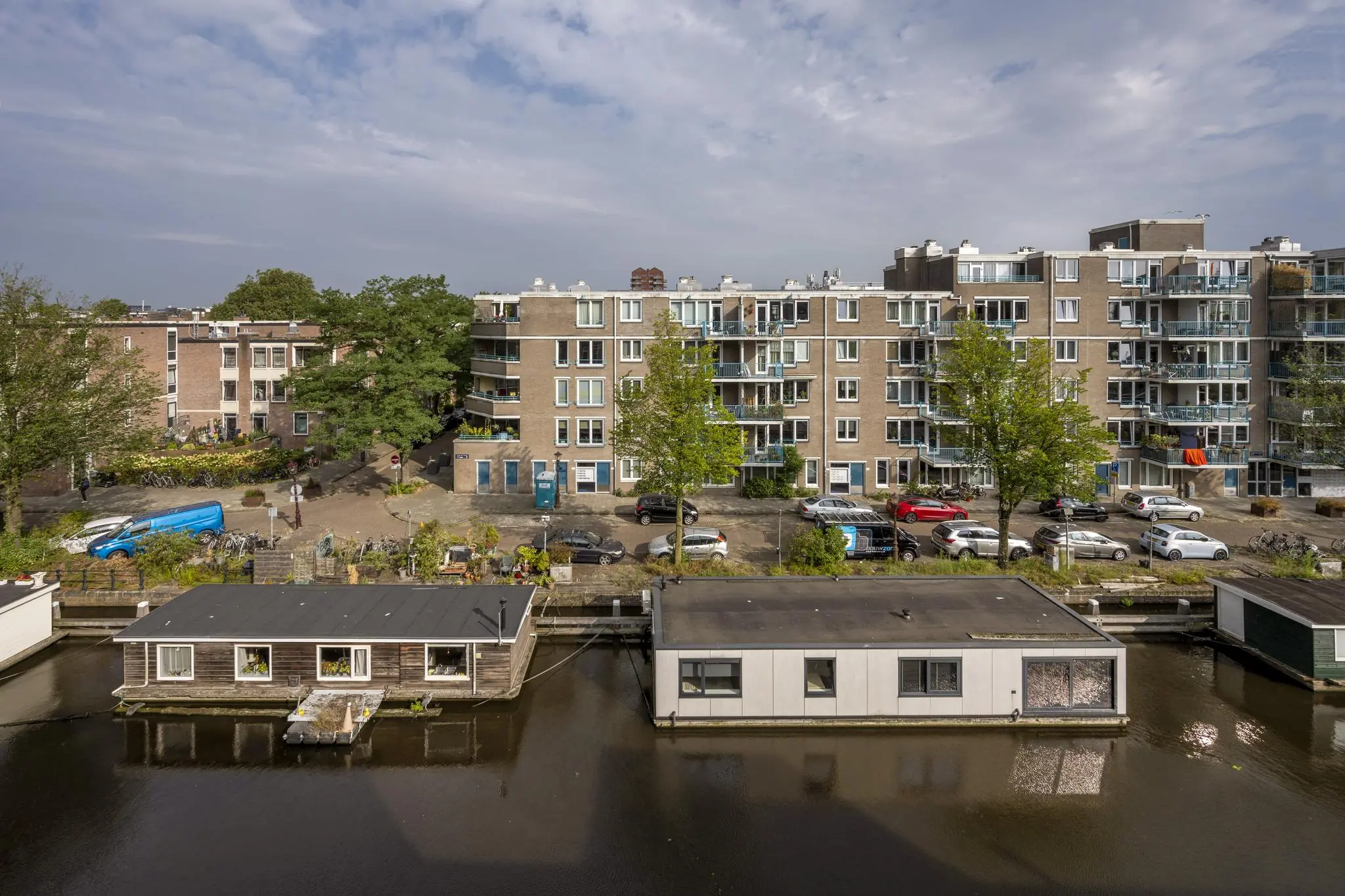 Woonboten aan een gracht met op de achtergrond appartementen aan het WG-plein in Amsterdam.