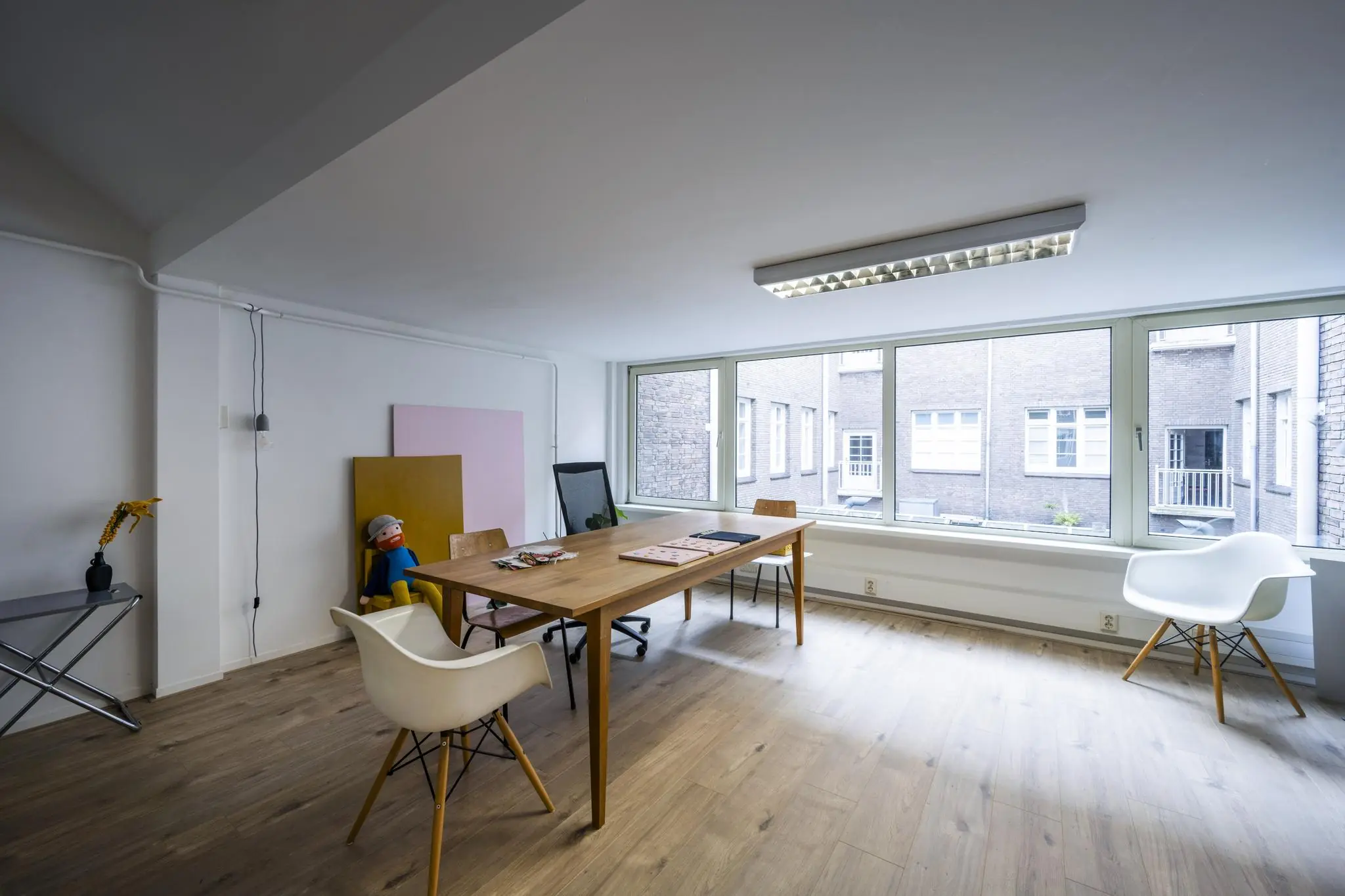 Licht en modern kantoor aan het WG-plein met houten vloer, grote ramen en een vergadertafel.