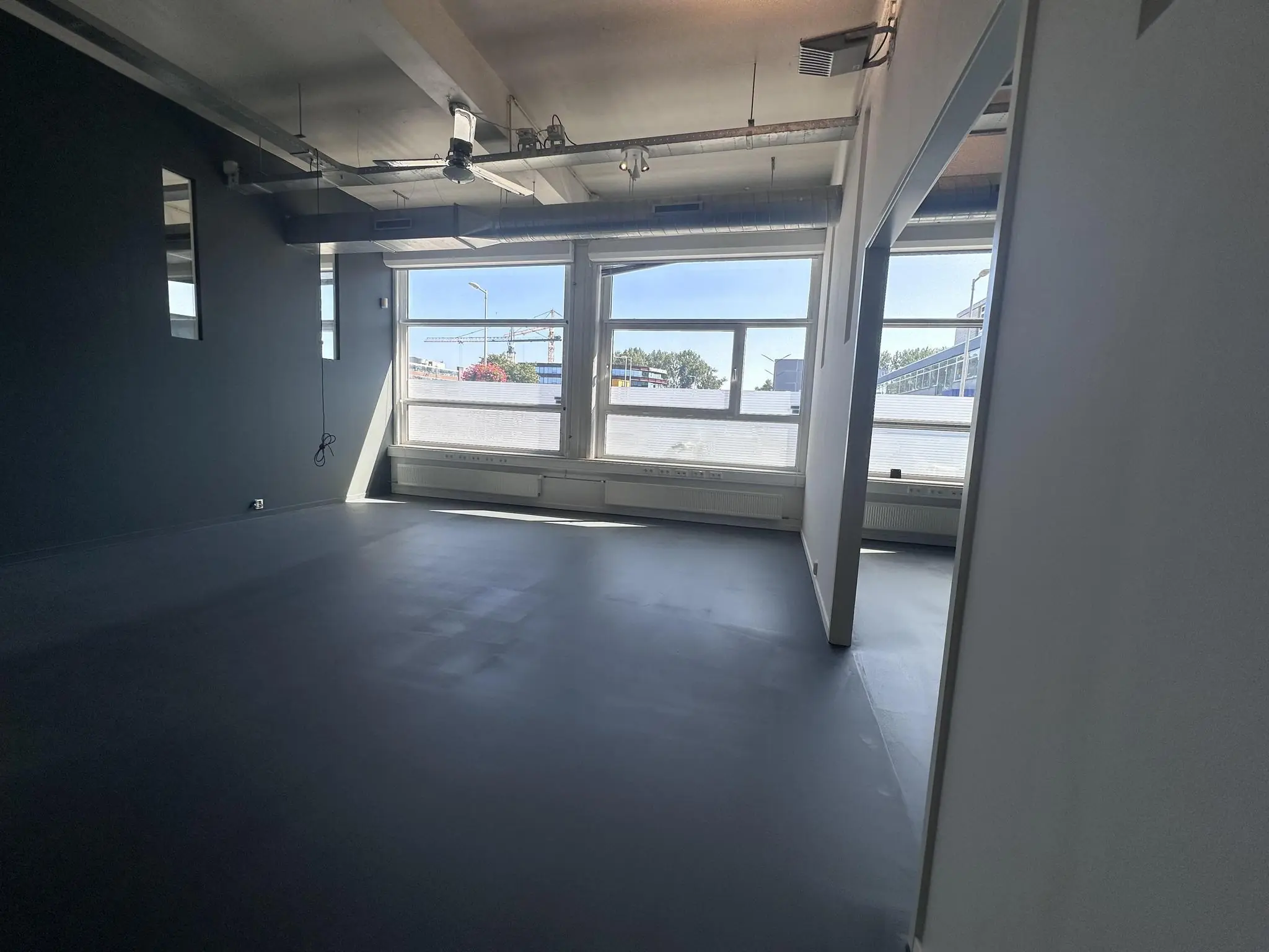 Licht industrieel kantoorruimte aan de Pilotenstraat met grote ramen en zicht op buiten.