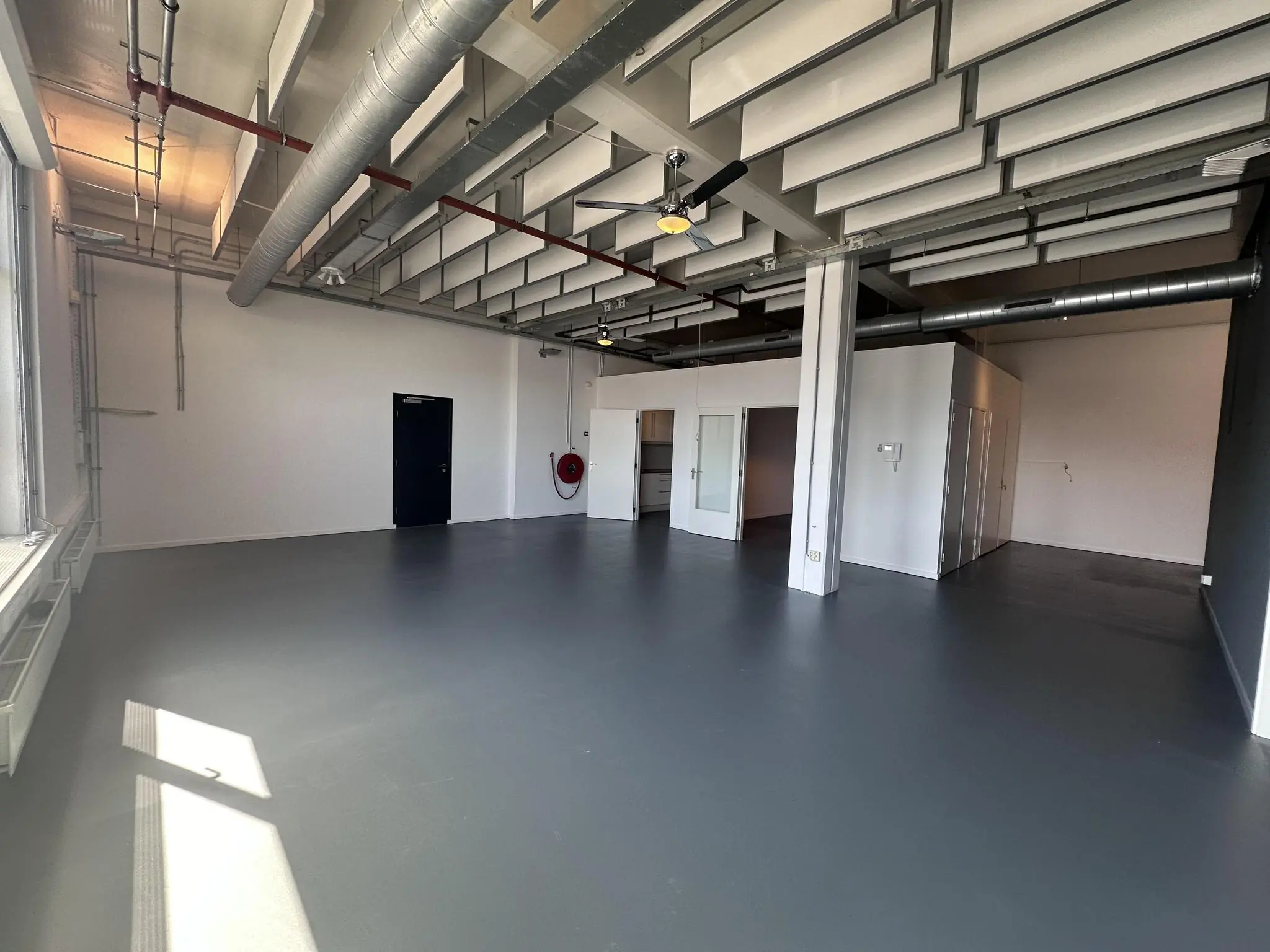 Leeg bedrijfsruimte-interieur aan de Pilotenstraat met industrieel plafond, grijze vloer en aparte kantoorunits.