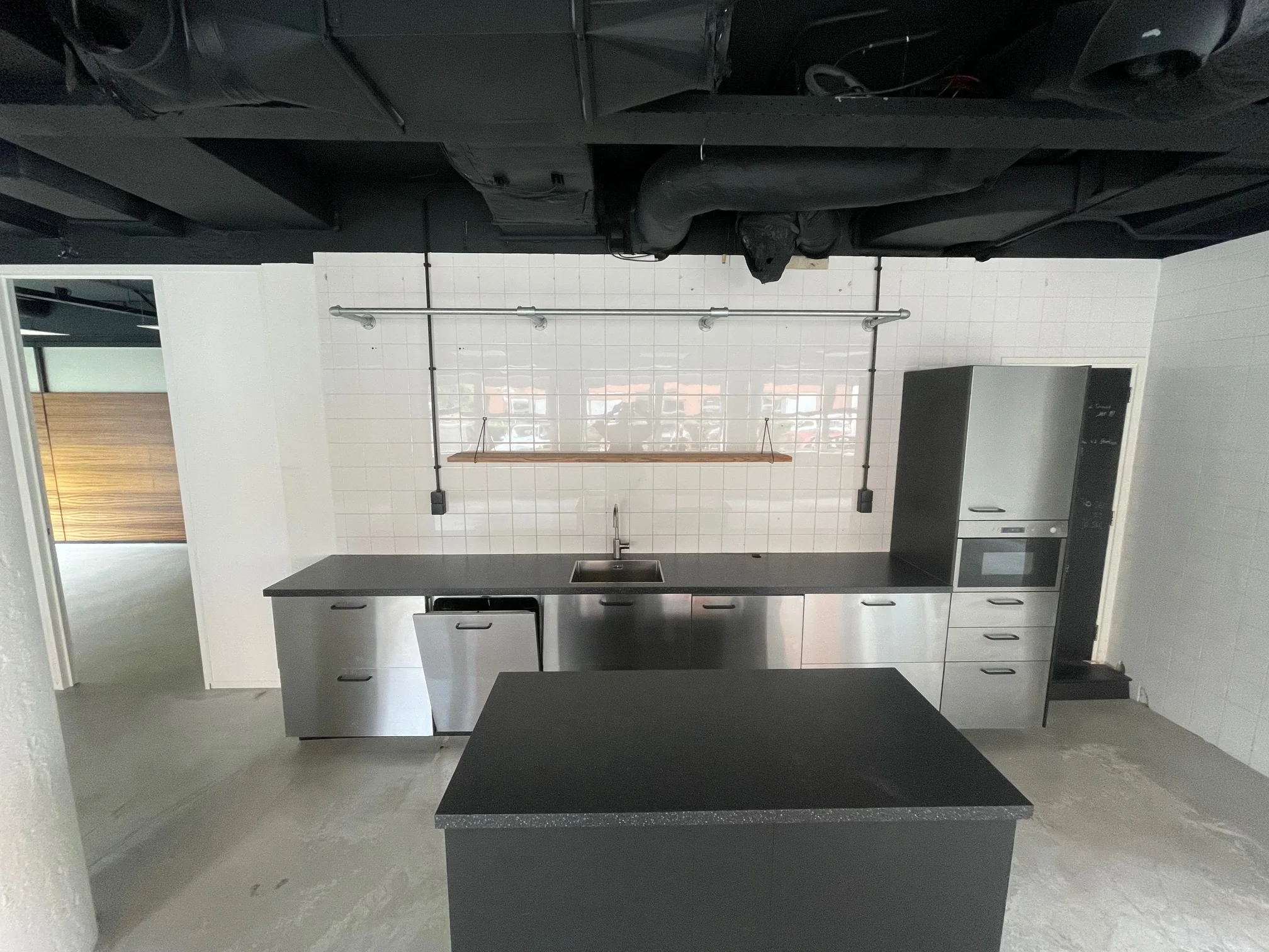 Moderne industriële keuken met roestvrijstalen kasten, zwarte details en een witte betegelde achterwand.