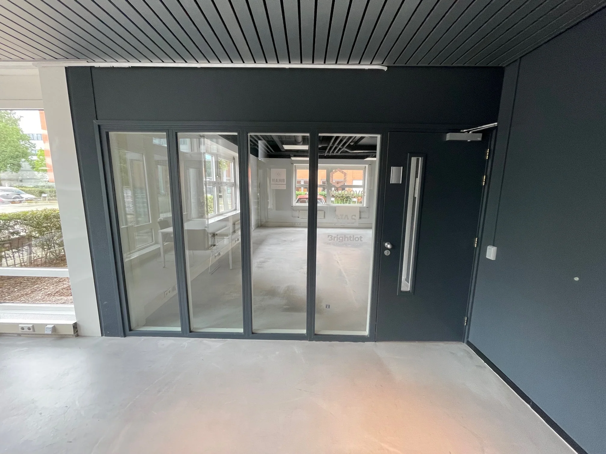 Glazen entree met zwarte kozijnen en deur van het kantoorpand Brightlot.