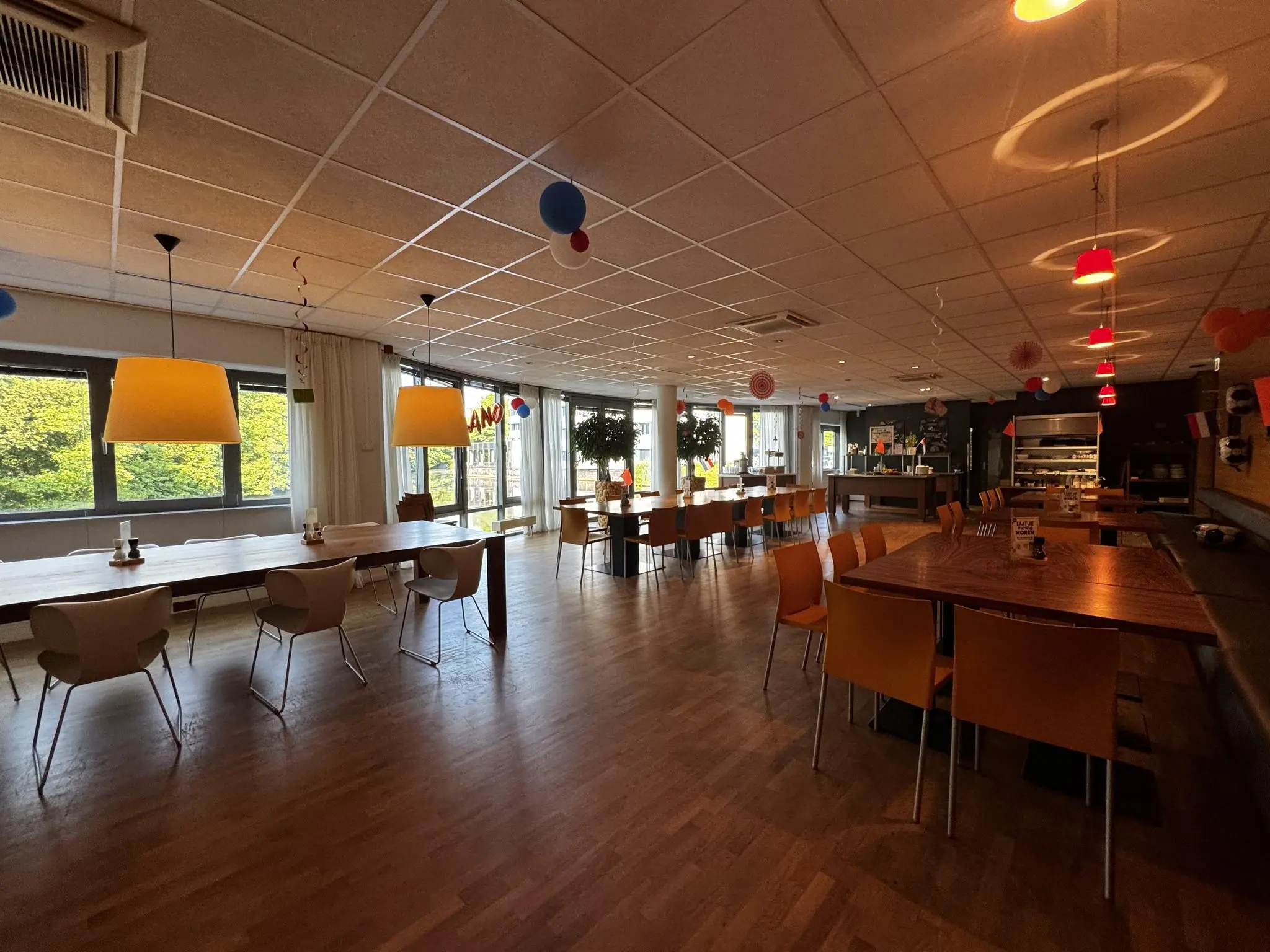 Moderne bedrijfskantine aan de Softwareweg met kleurrijke stoelen, grote ramen en sfeerverlichting.