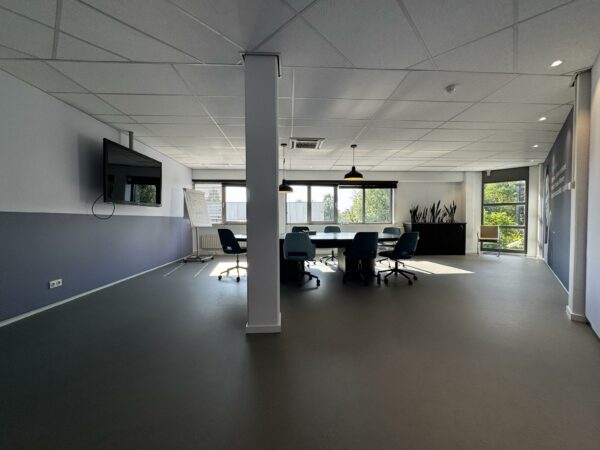 Moderne vergaderruimte bij Softwareweg met grote vergadertafel, stoelen, presentatiescherm en daglicht van meerdere ramen.