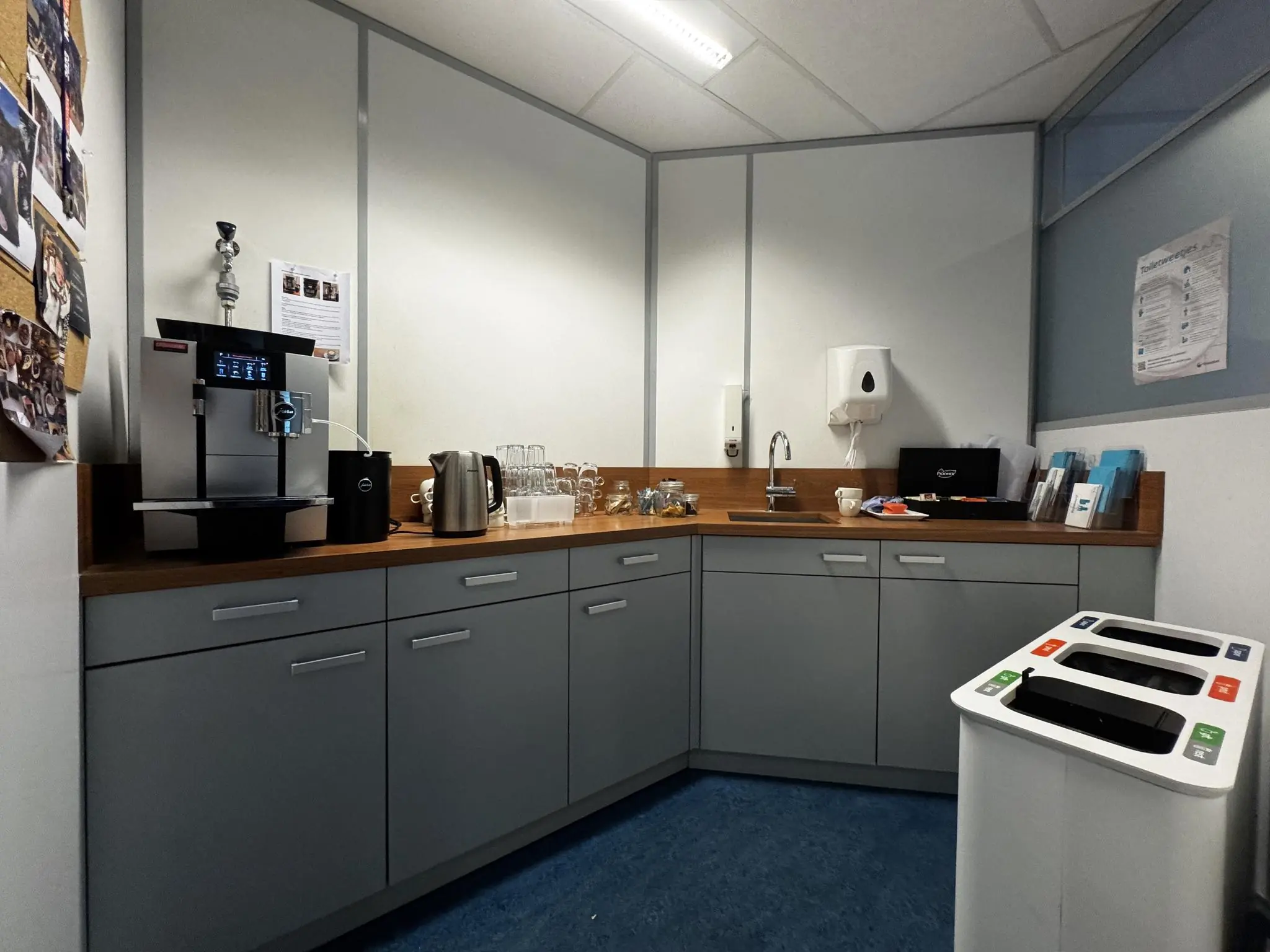 Kleine bedrijfskeuken met een koffiezetapparaat, waterkoker, spoelbak en afvalscheidingsbak.