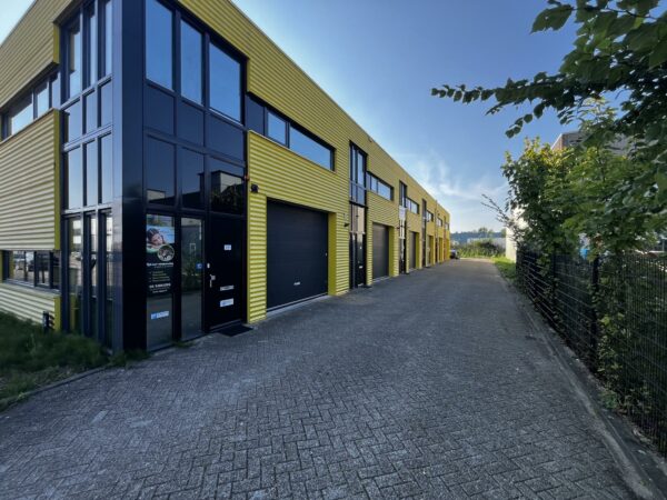 Bedrijfsverzamelgebouw met gele gevels aan de Ambachtsweg met meerdere units en roldeuren.