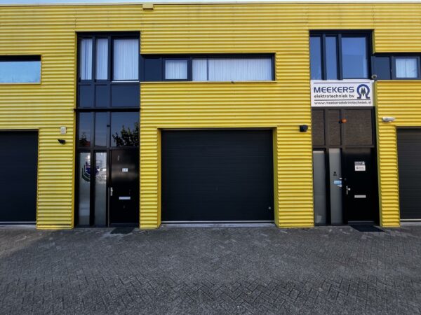 Bedrijfspand met gele gevel en het logo van Meekers Elektrotechniek BV aan de Ambachtsweg.