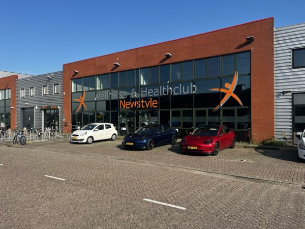 Vooraanzicht van wellness- en healthclub Newstyle aan de Ambachtsweg met geparkeerde auto's voor de ingang.