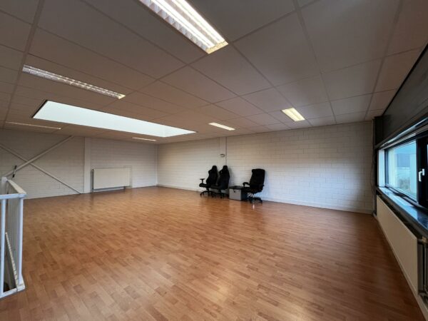 Leeg kantoorruimte met laminaatvloer, systeemplafond, grote ramen en enkele bureaustoelen aan de muur op Ambachtsweg.