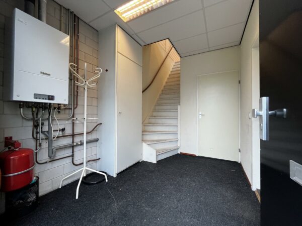 Ingangsruimte aan de Ambachtsweg met trap, cv-installatie van Vaillant en technische leidingen.