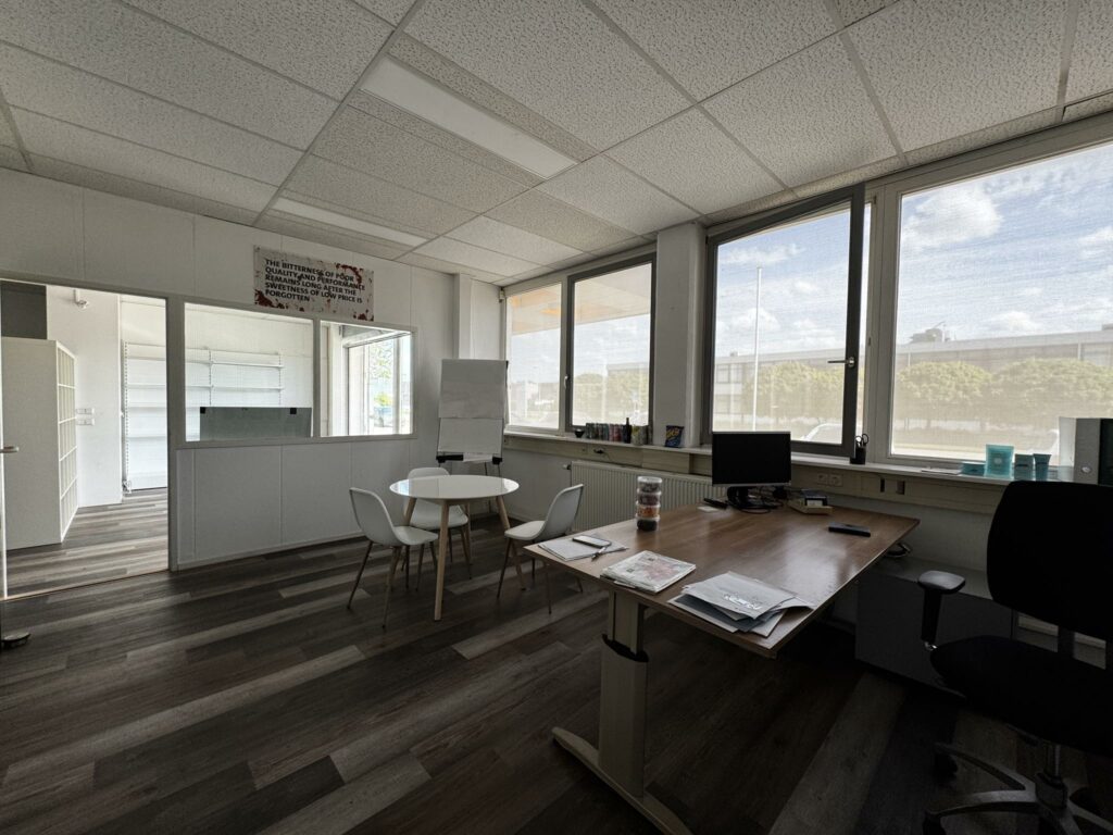Modern ingericht kantoor aan de Lorentzweg met bureau, vergadertafel en grote ramen met daglicht.