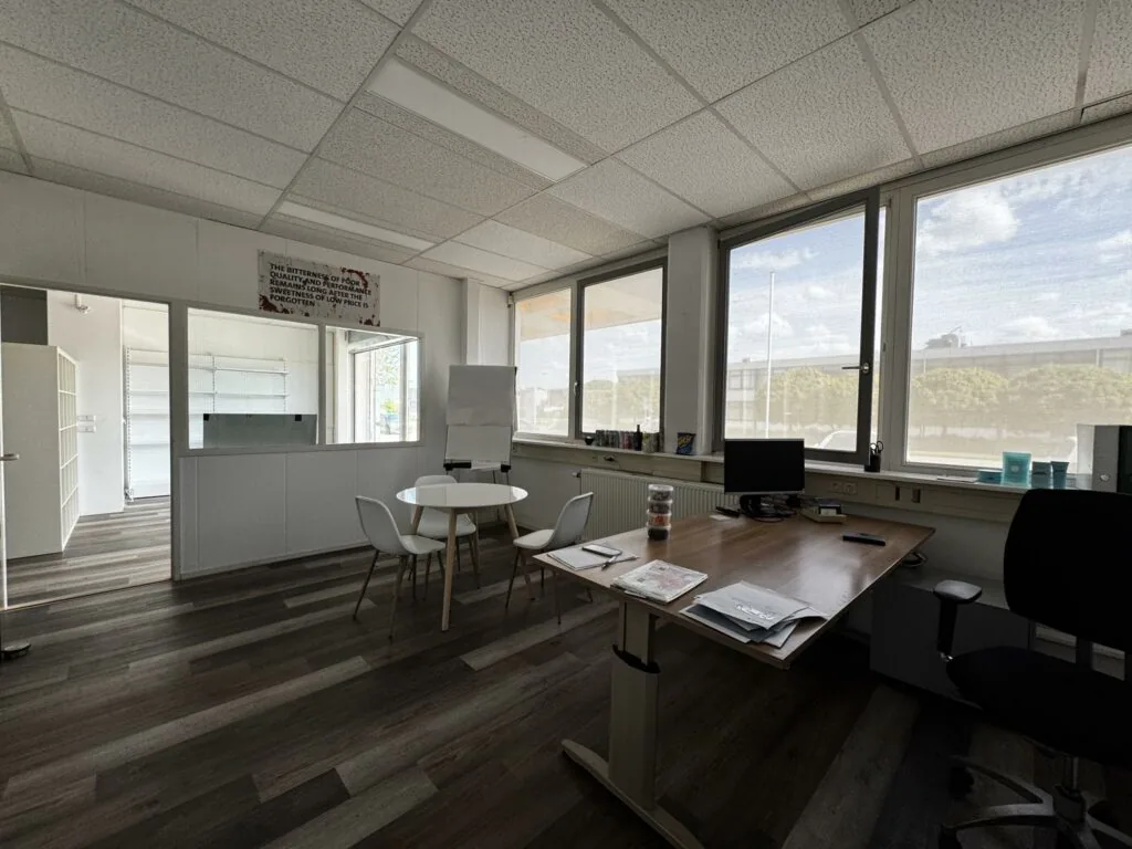 Modern ingericht kantoor aan de Lorentzweg met bureau, vergadertafel en grote ramen met daglicht.