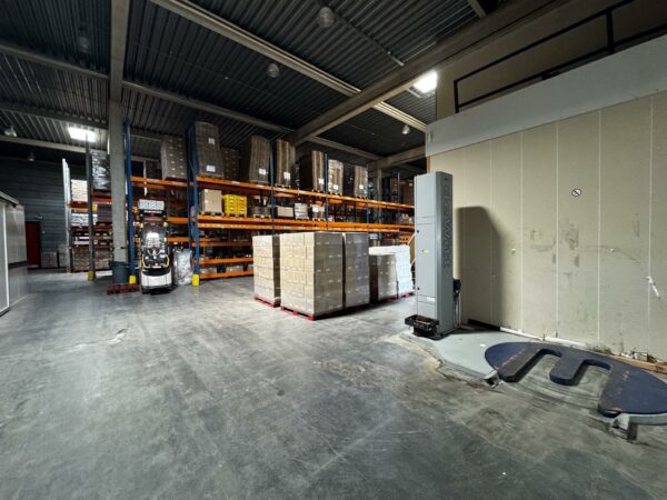 Magazijn aan de Lorentzweg met hoge opslagtrekken, een stapel pallets en een De Witt wikkelmachine op de voorgrond.