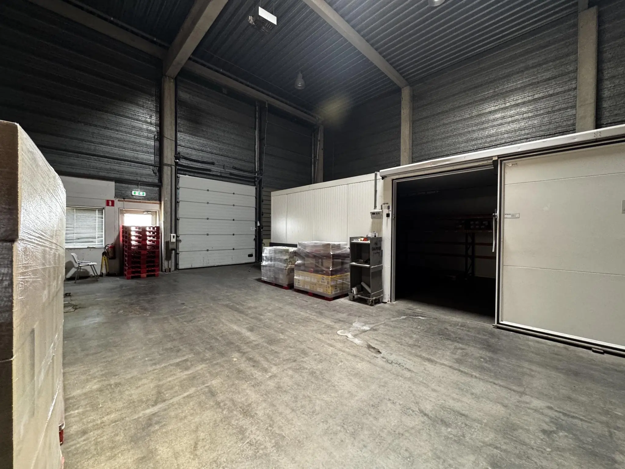 Ruime opslagloods aan de Lorentzweg met opgestapelde pallets en een geopende koelcel.