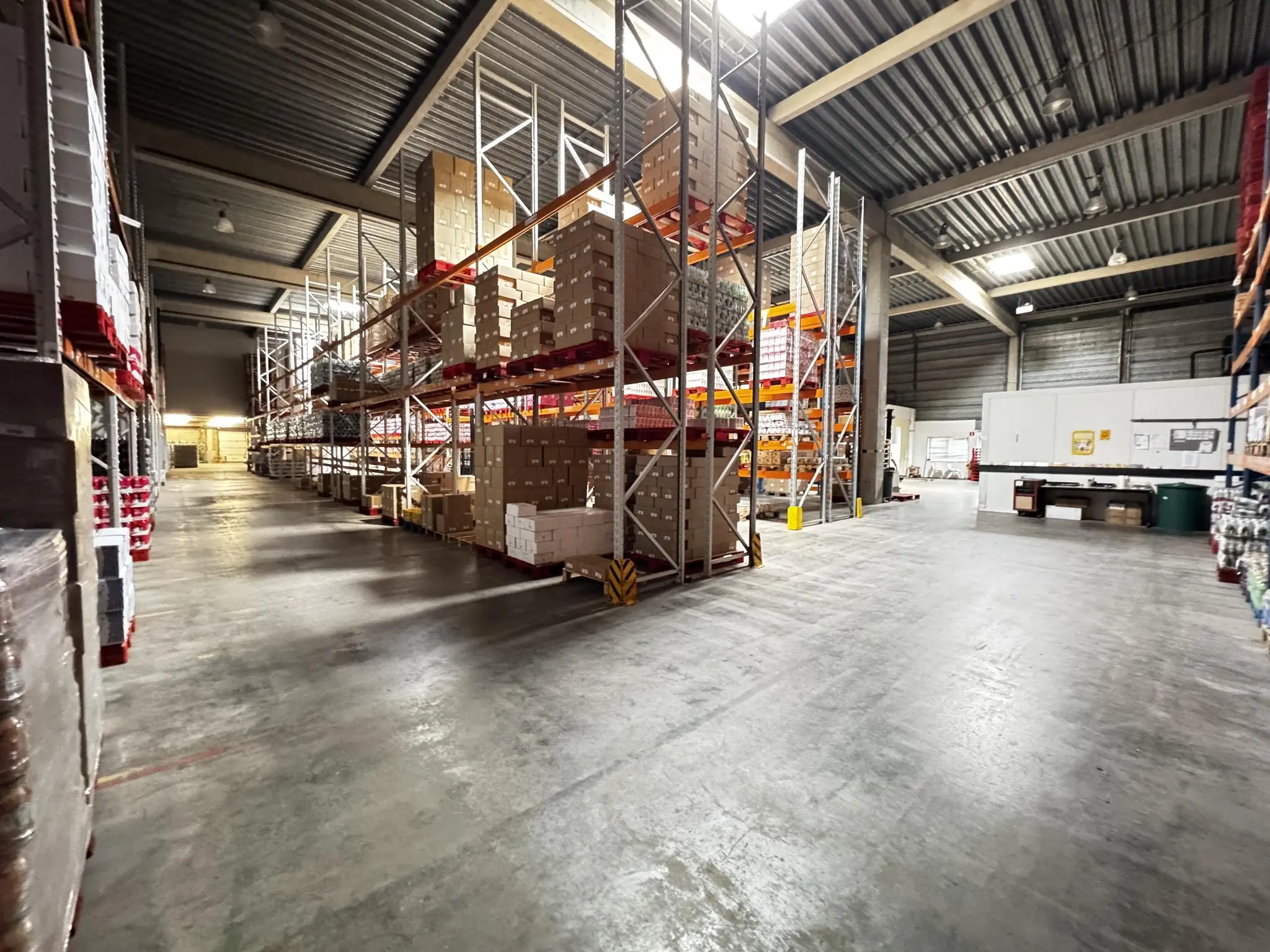 Magazijn aan de Lorentzweg met hoge stellingen vol dozen en brede looppaden.