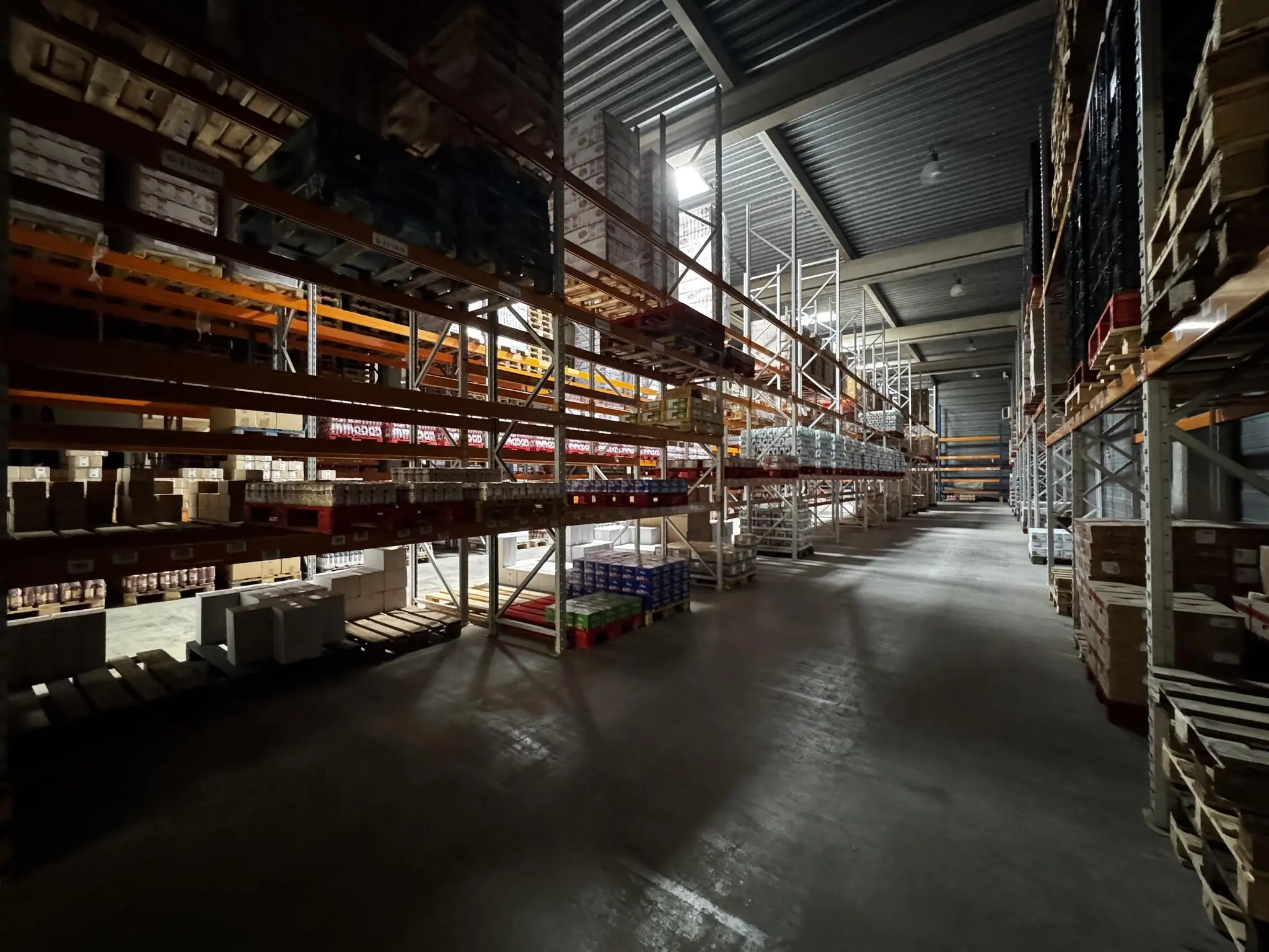 Magazijn aan de Lorentzweg met hoge stellingen vol opgeslagen goederen en dozen.