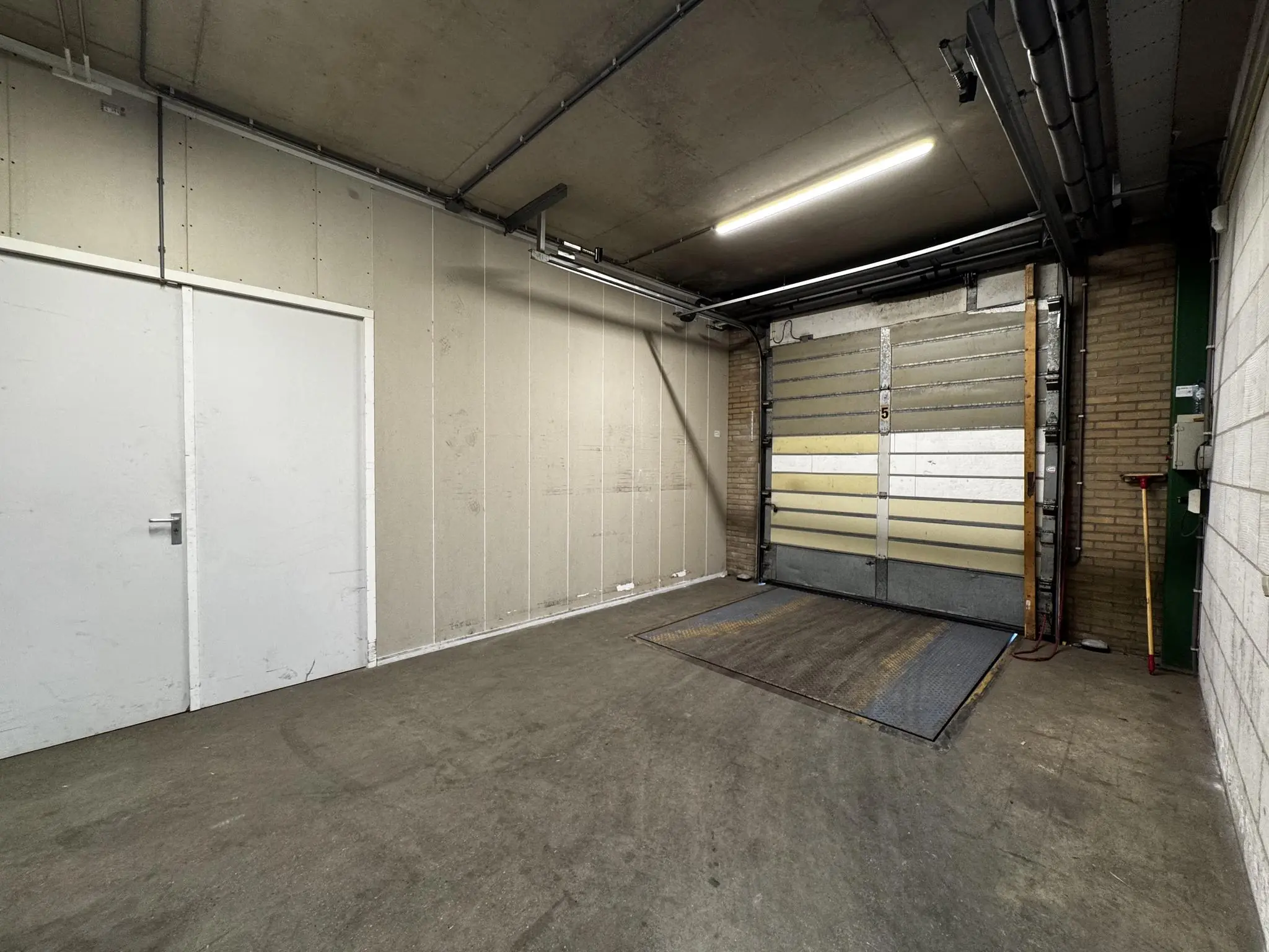 Leeg industriëel laadperron met gesloten overheaddeur aan de Lorentzweg.