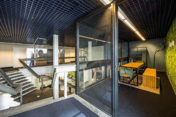 Modern kantoorinterieur aan de Vliegtuigstraat met open trappenhuis en glazen vergaderruimte met groene moswand.