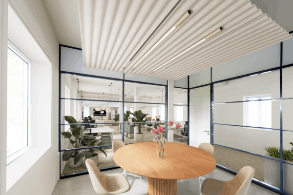 Moderne vergaderruimte aan de Vliegtuigstraat met ronde houten tafel, glazen wanden en uitzicht op een open kantoorruimte.