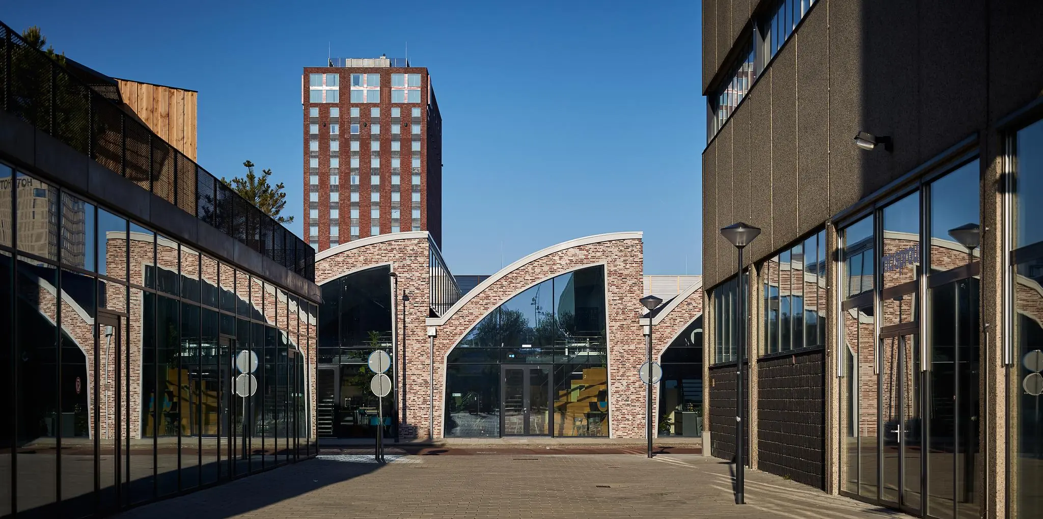 Straatbeeld van de Abram Dudok van Heelstraat met moderne bakstenen gebouwen en een hoge woontoren op de achtergrond.