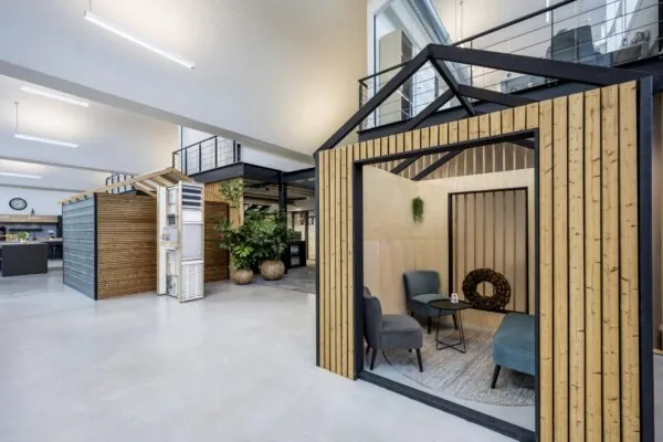 Moderne kantoorruimte aan de Abram Dudok van Heelstraat met houten vergaderruimtes in de vorm van huisjes en een open, industrieel interieurontwerp.