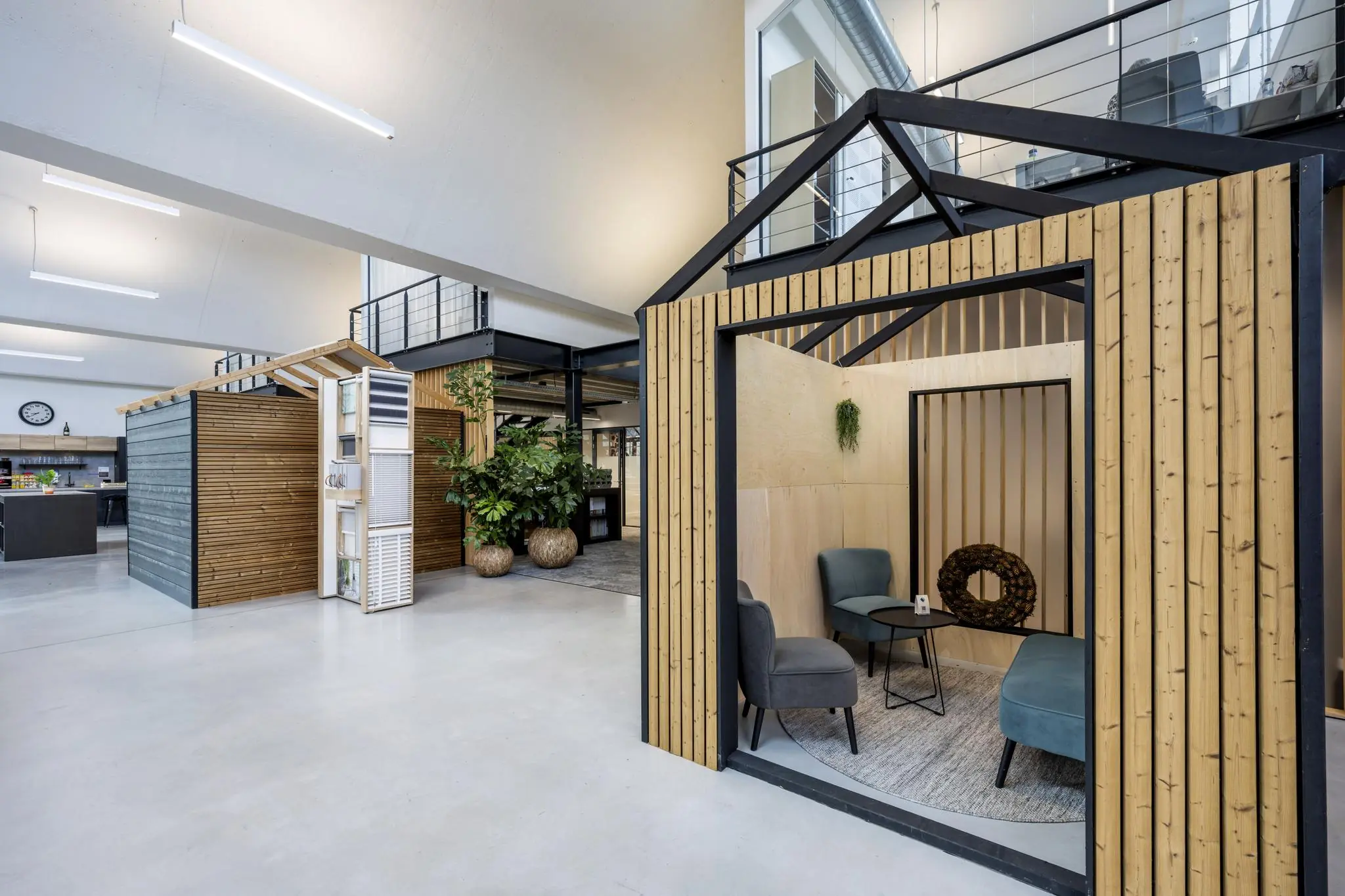 Moderne kantoorruimte aan de Abram Dudok van Heelstraat met houten vergaderruimtes in de vorm van huisjes en een open, industrieel interieurontwerp.