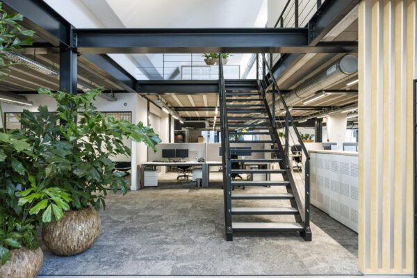 Moderne kantoorruimte aan de Abram Dudok van Heelstraat met een open trap, werkplekken en grote planten.