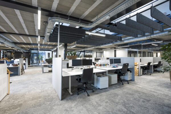Moderne open kantoorruimte aan de Abram Dudok van Heelstraat met werkplekken, bureaustoelen en akoestische panelen aan het plafond.