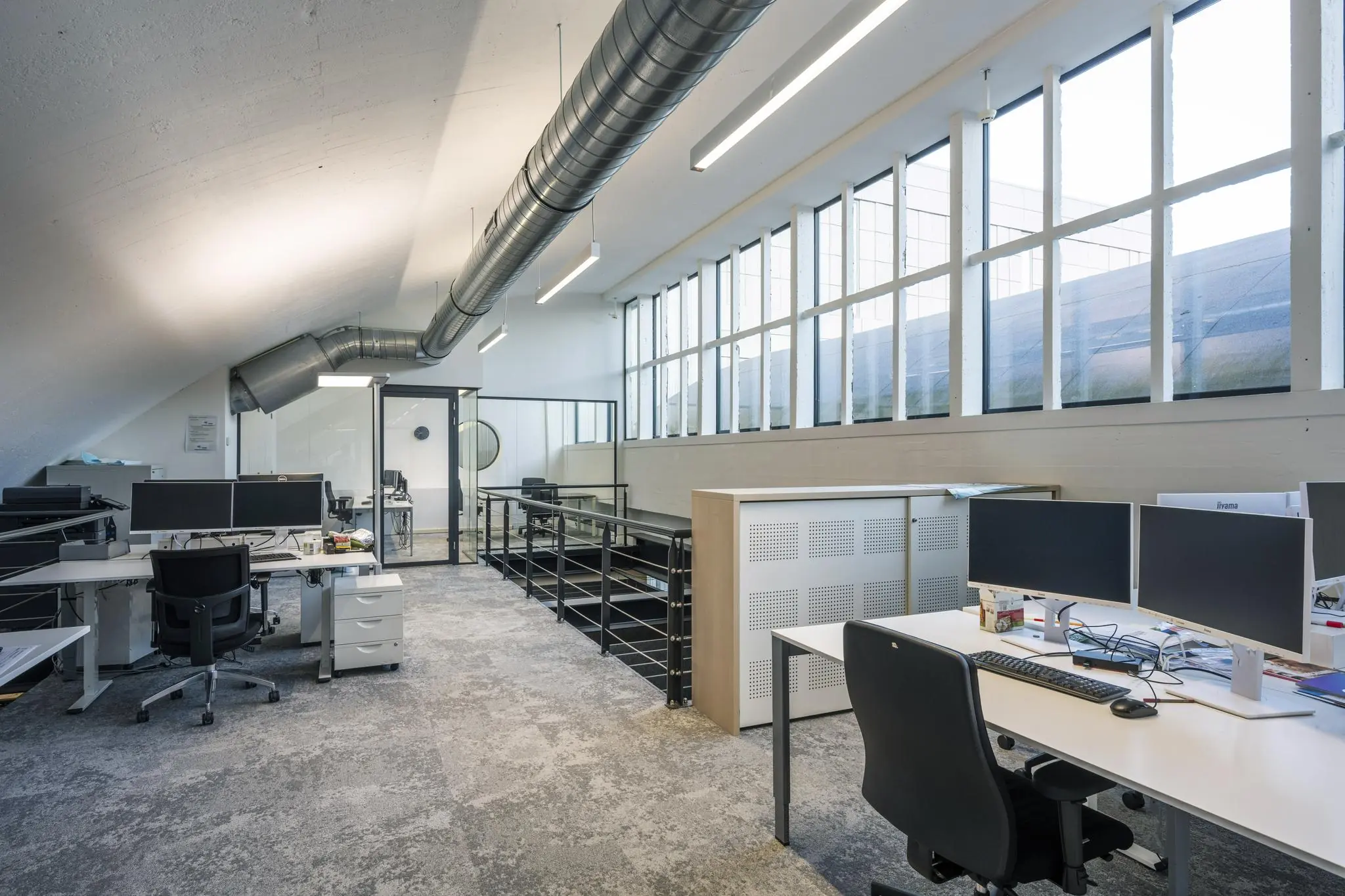 Modern kantoorinterieur aan de Abram Dudok van Heelstraat met werkplekken, veel daglicht en industriële details zoals zichtbare ventilatiebuizen.