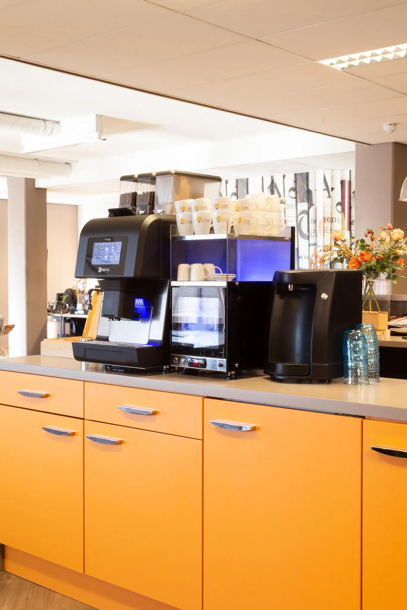 Koffiecorner met moderne koffiemachine, kopjes en oranje keukenkastjes aan de Zaagmolenlaan.