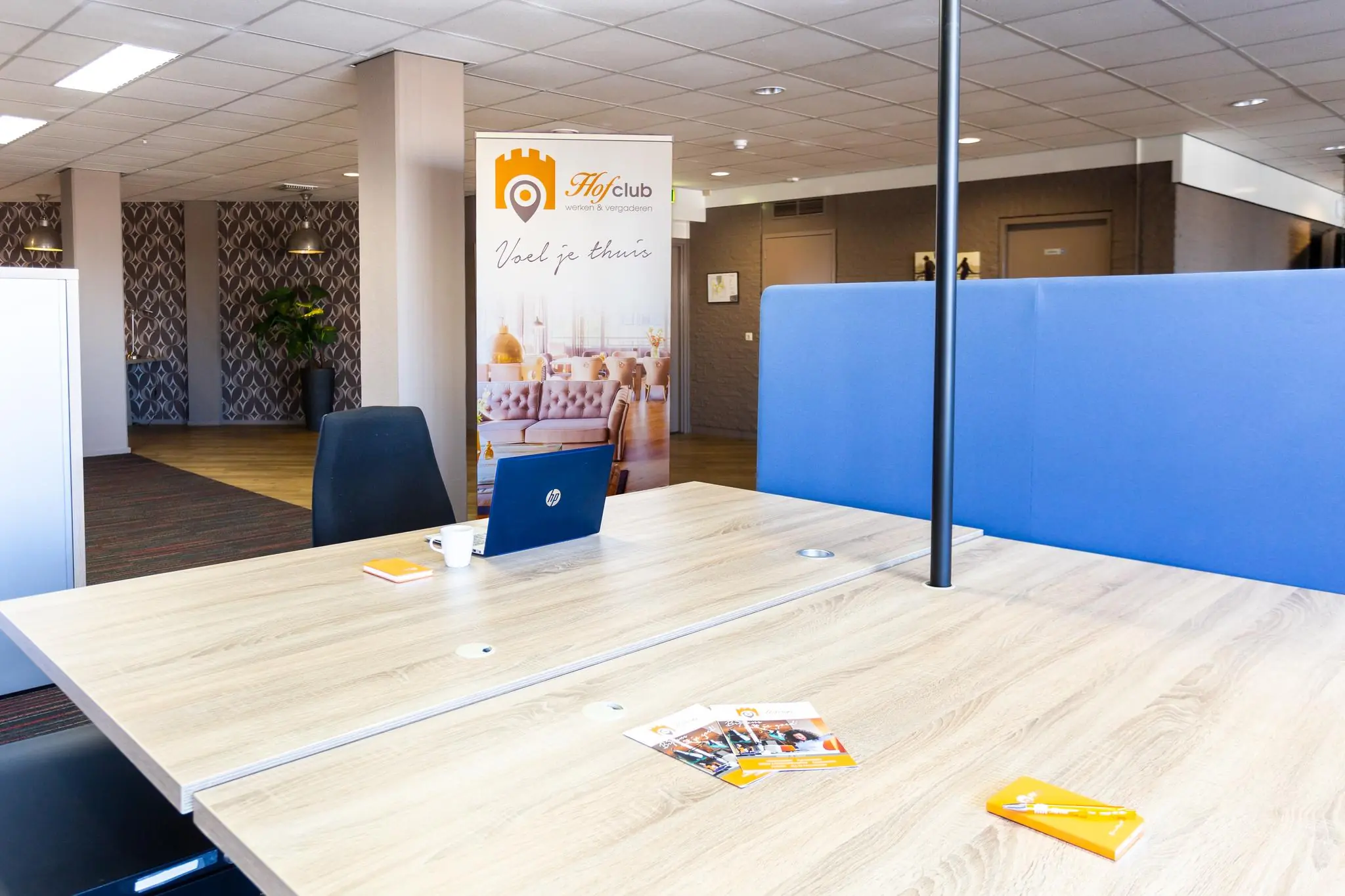 Moderne en lichte flexwerkruimte in Hofclub Zaagmolenlaan met werkplekken, laptop en promotiemateriaal.