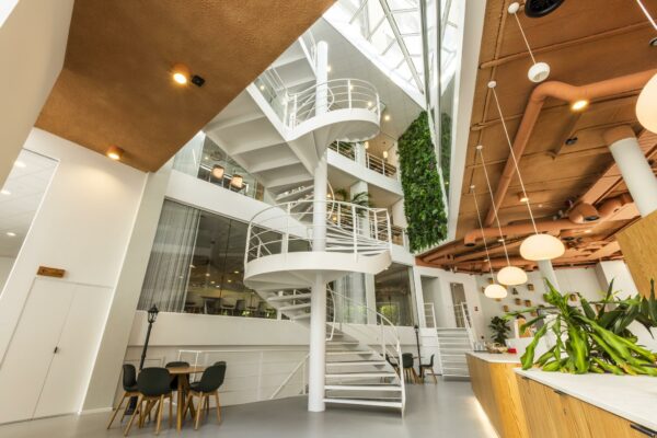 Moderne kantoorruimte aan de Bezuidenhoutseweg met een witte wenteltrap, groene plantenwand en strak interieurdesign.
