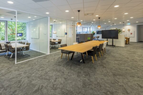 Moderne kantoorruimte aan de Bezuidenhoutseweg met glazen vergaderruimtes, grote houten vergadertafels en een flexibele opstelling.