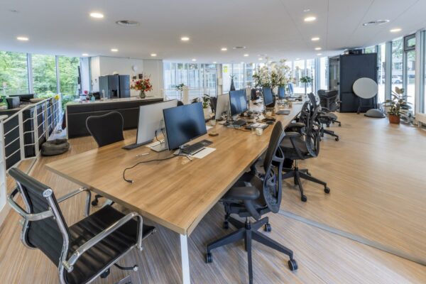 Moderne open kantoorruimte aan de Bezuidenhoutseweg met werkplekken, computers en grote ramen met veel daglicht.