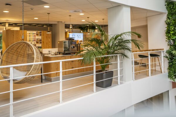 Moderne kantoorruimte aan de Bezuidenhoutseweg met een koffiehoek, hangstoel en groene accenten.