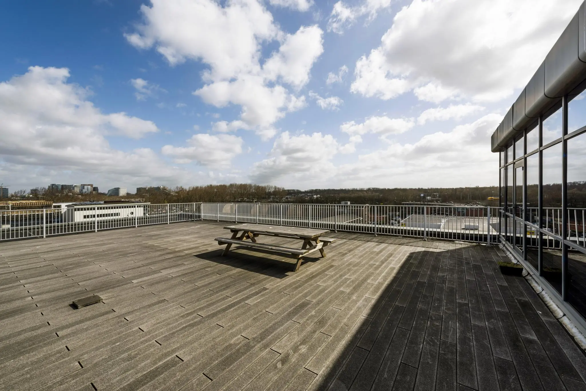Dakterras met houten picknicktafel en uitzicht over bedrijventerrein aan de Anthony Fokkerweg.