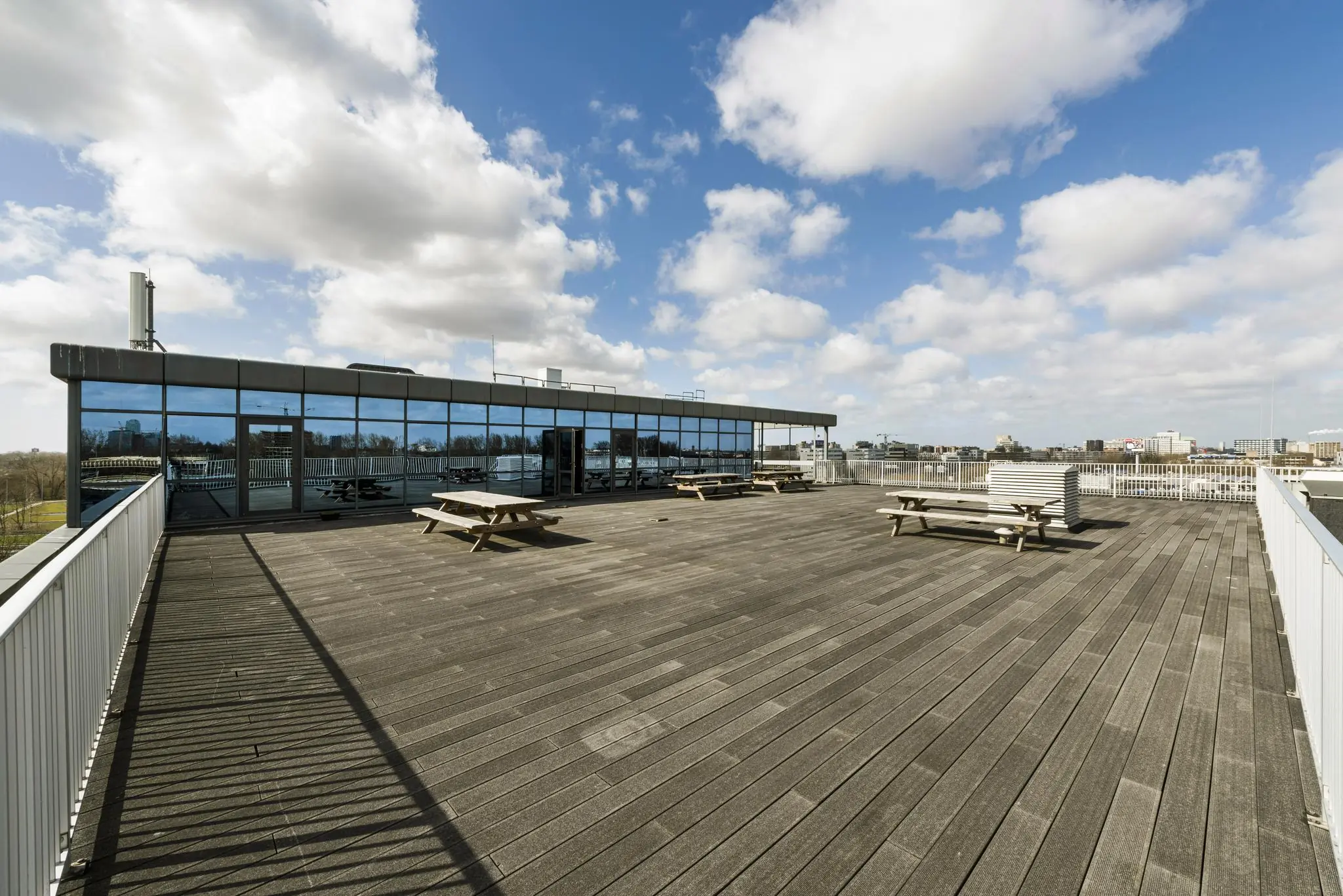 Ruim dakterras met houten vlonders, picknicktafels en uitzicht op de stad bij Anthony Fokkerweg.