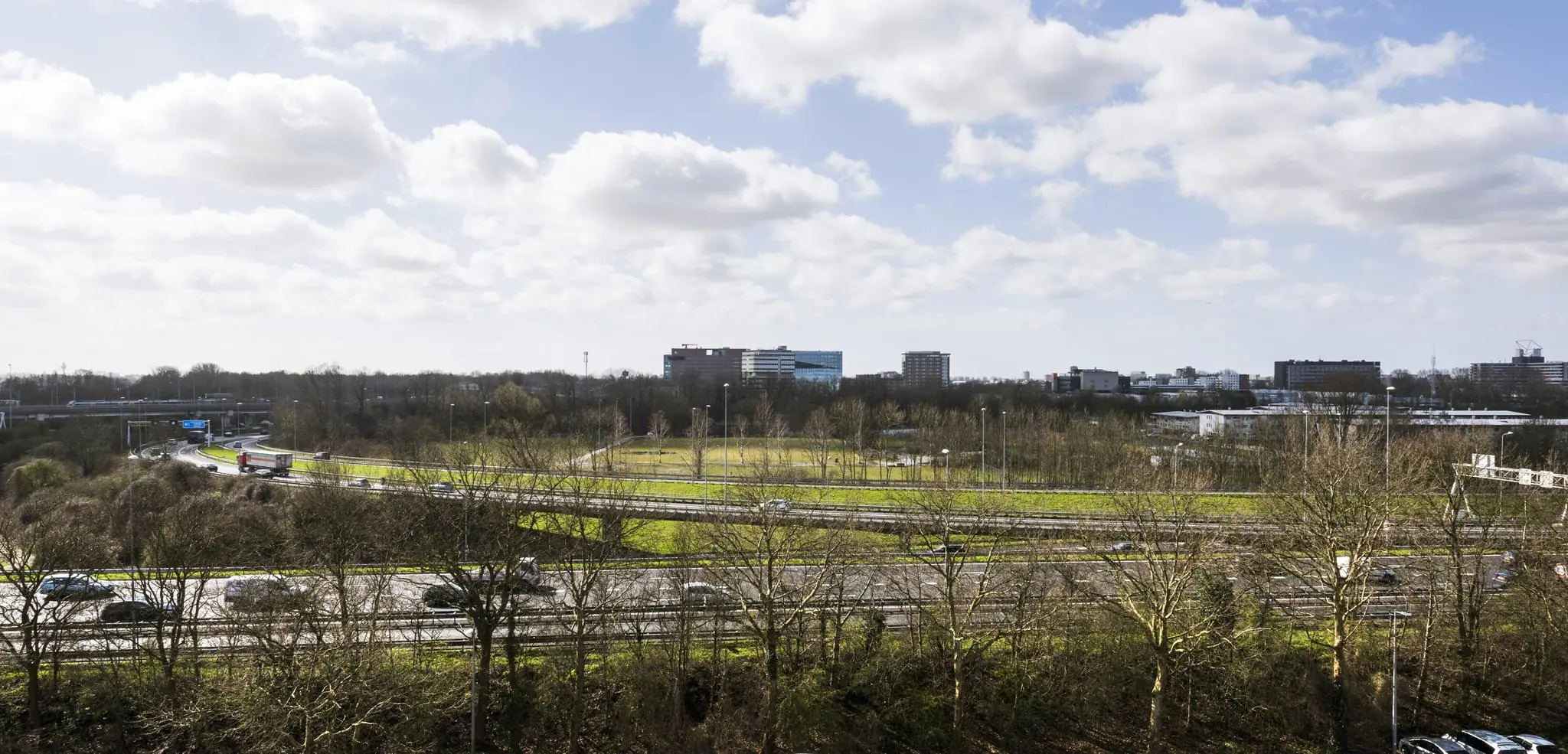 Overzicht van de Anthony Fokkerweg met omliggende snelwegen, groenstroken en kantoorgebouwen onder een deels bewolkte lucht.