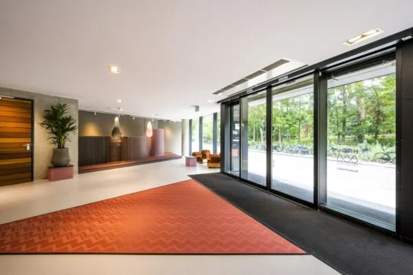 Moderne entreehal aan de Generaal Vetterstraat met grote glazen schuifdeuren, stijlvolle inrichting en uitzicht op fietsen buiten.