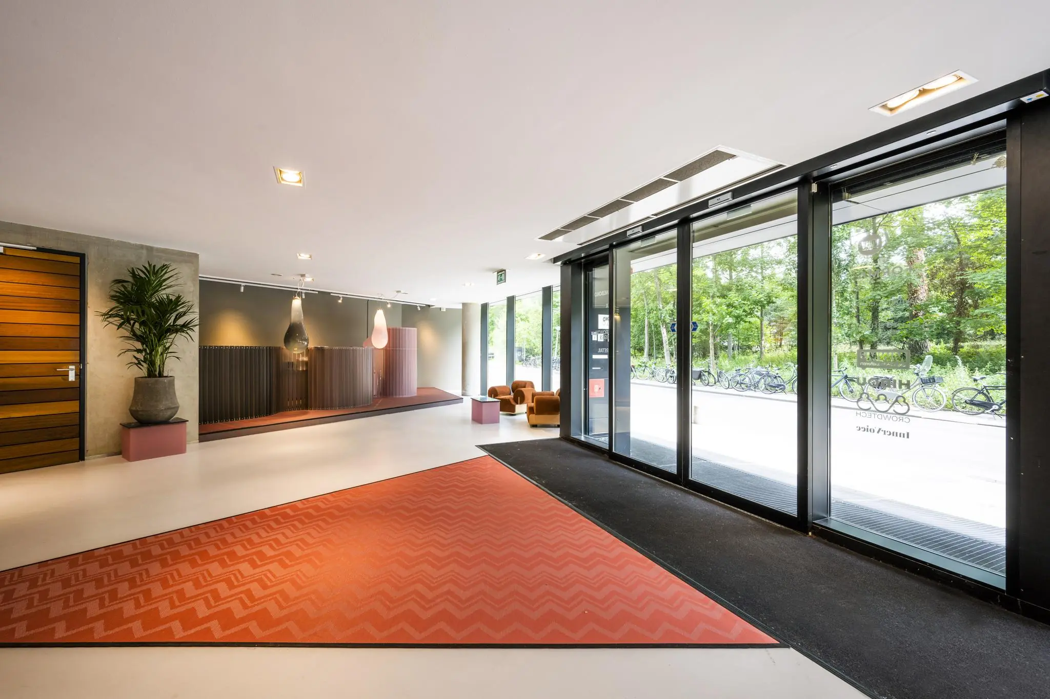 Moderne entreehal aan de Generaal Vetterstraat met grote glazen schuifdeuren, stijlvolle inrichting en uitzicht op fietsen buiten.