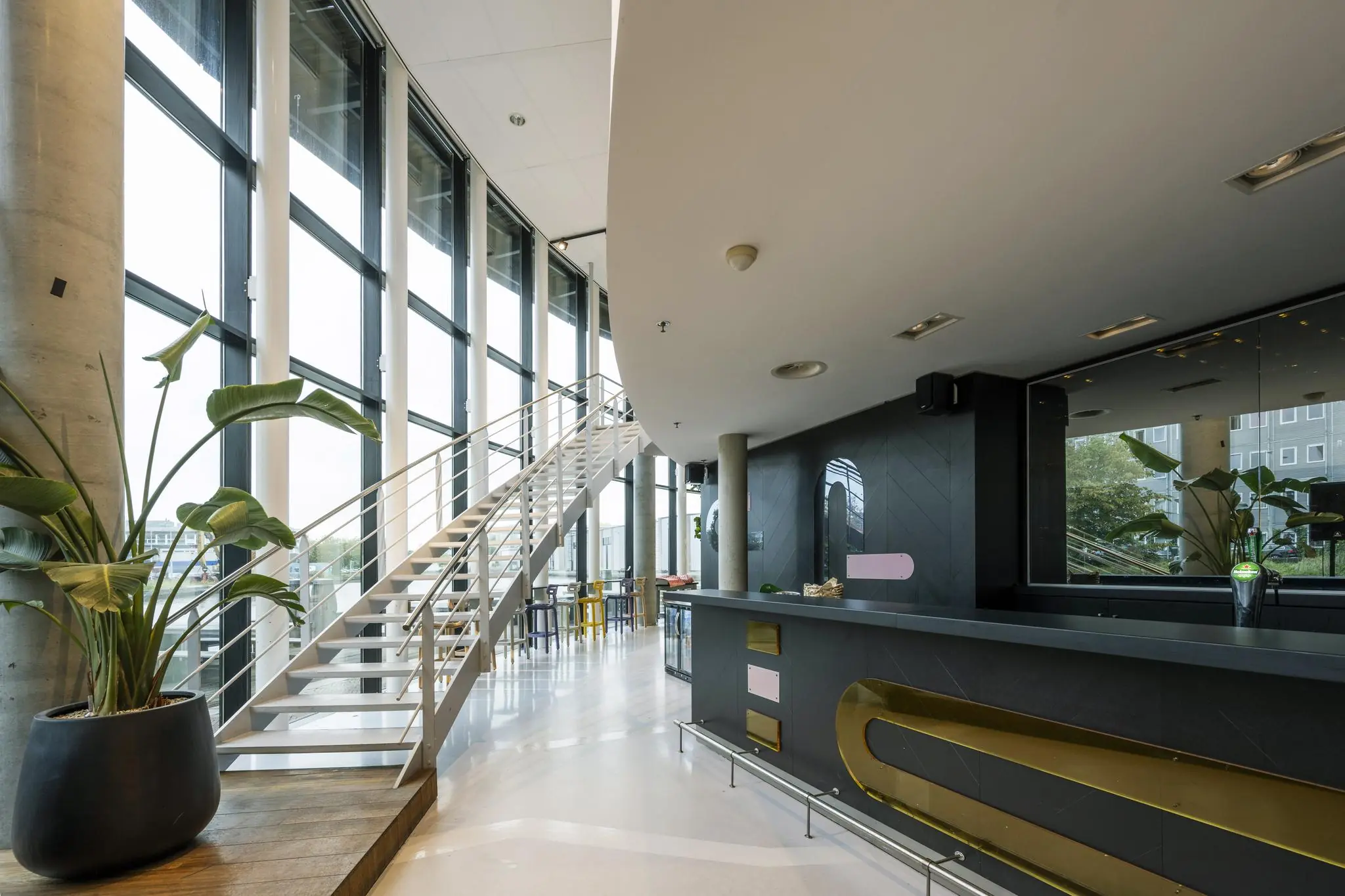 Moderne lobby met grote raampartijen, een zwarte balie en een witte trap in een gebouw aan de Generaal Vetterstraat.