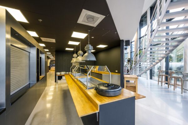 Moderne bedrijfskeuken met uitgiftebuffet en een trap naar de bovenverdieping aan de Generaal Vetterstraat.