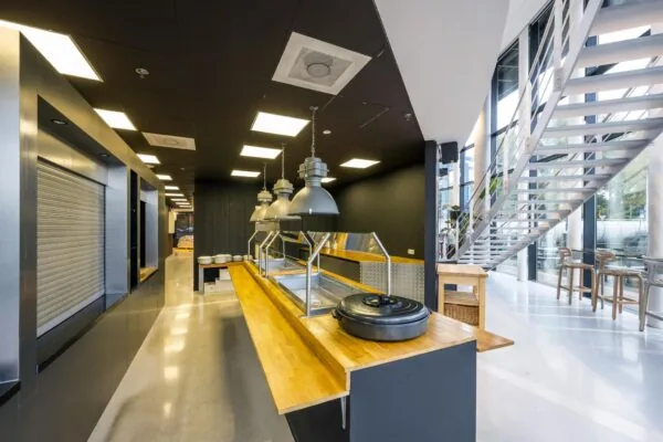 Moderne bedrijfskeuken met uitgiftebuffet en een trap naar de bovenverdieping aan de Generaal Vetterstraat.