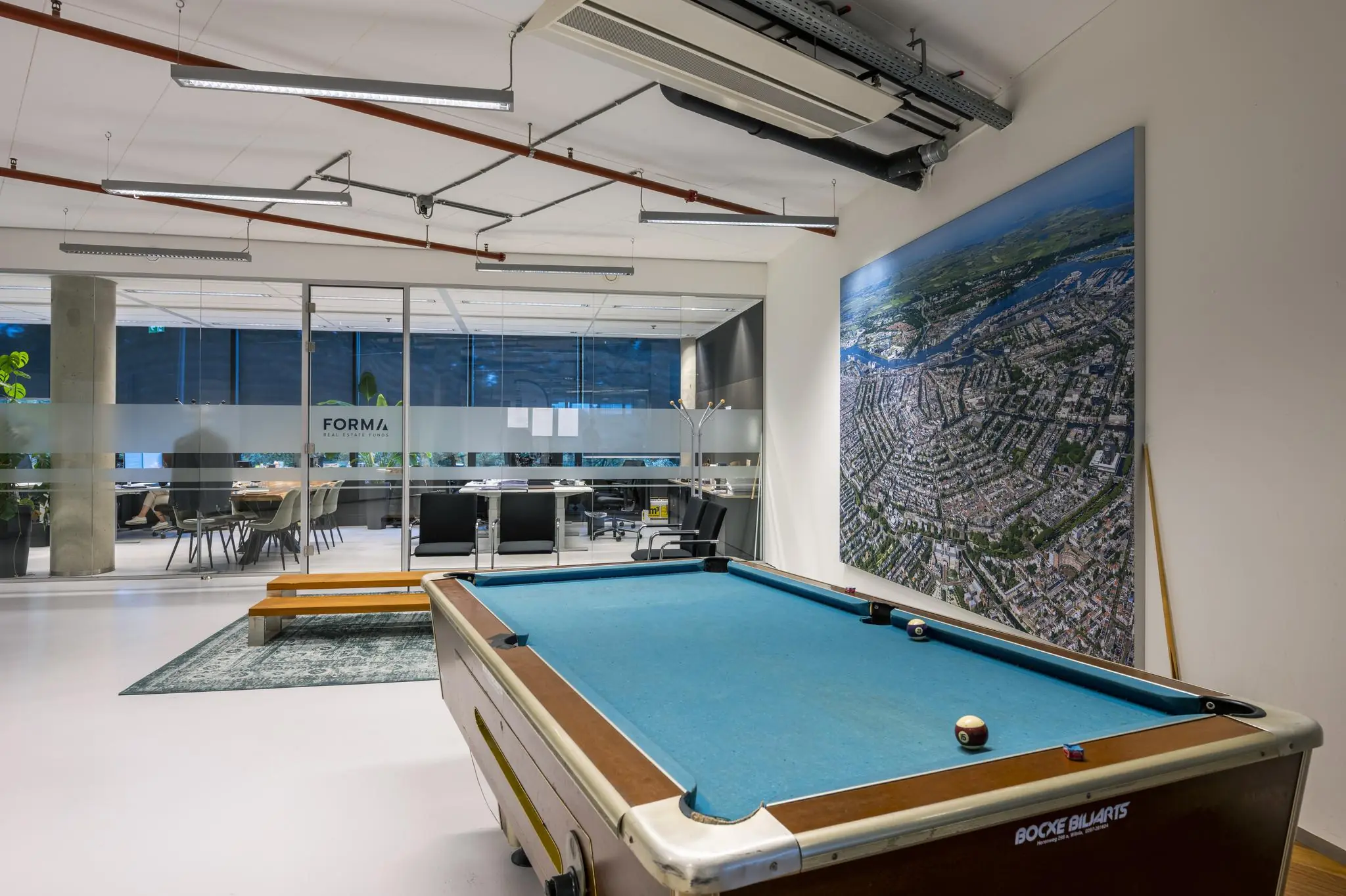 Moderne kantoorruimte aan de Generaal Vetterstraat met een pooltafel, vergaderruimte en grote luchtfoto aan de muur.