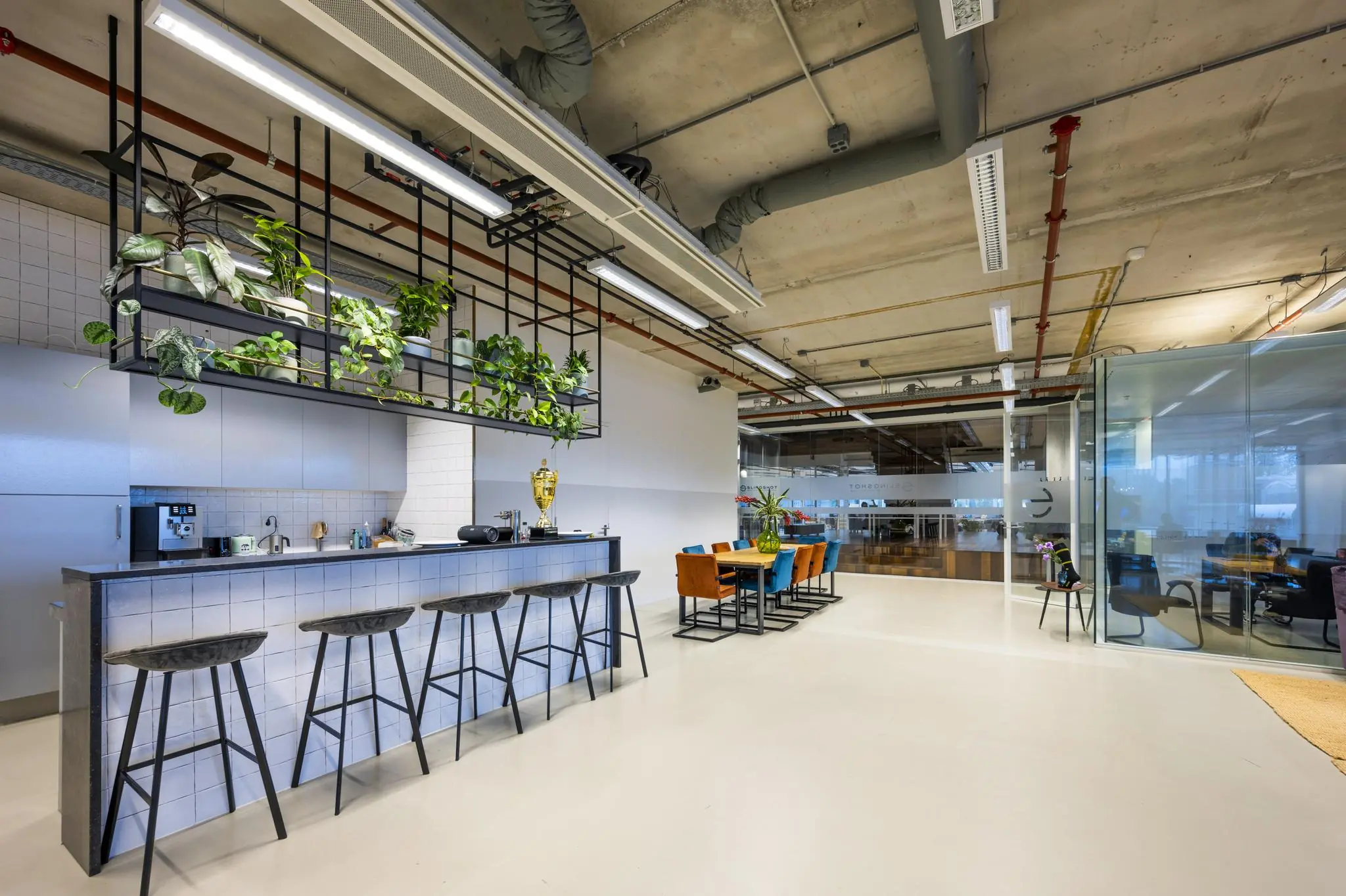 Moderne kantoorruimte aan de Generaal Vetterstraat met een open keuken, hangende planten en kleurrijke vergaderruimte.