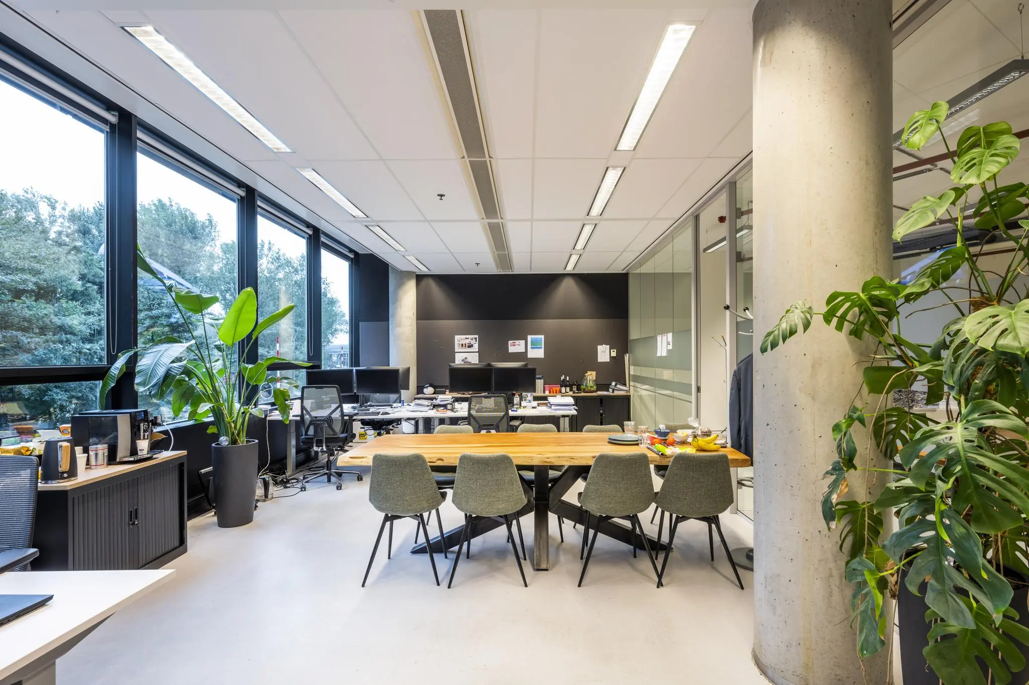 Moderne kantoorruimte aan de Generaal Vetterstraat met een grote houten vergadertafel, bureaus, planten en veel daglicht.