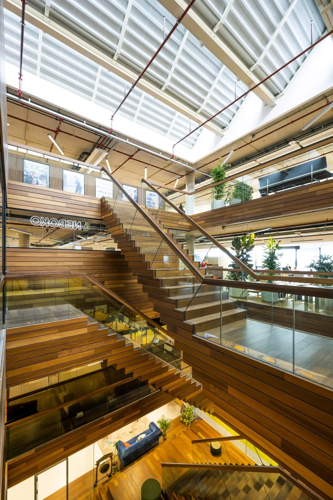 Moderne houten trappenhal met glazen balustrades in een licht atrium aan de Generaal Vetterstraat.