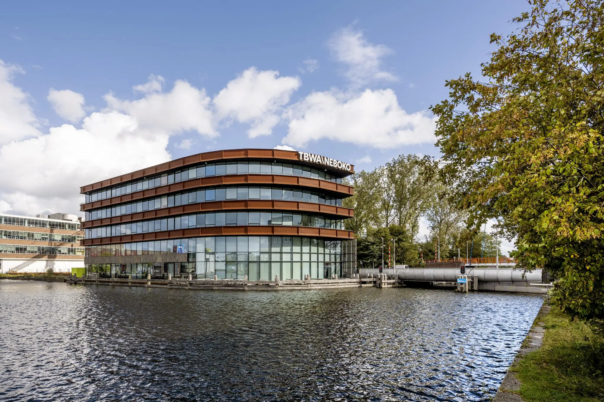 Modern kantoorgebouw aan het water aan de Generaal Vetterstraat in Amsterdam, met het logo van TBWANEBOKO op de gevel.