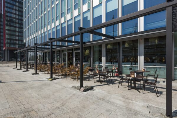 Terras met tafels en stoelen naast een modern kantoorgebouw aan het Mandelaplein.