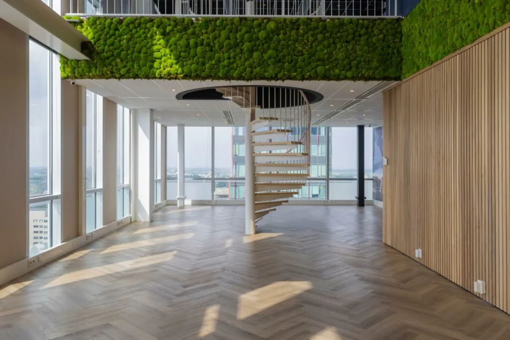 Licht en modern interieur op het Mandelaplein met houten visgraatvloer, groene moswand en spiraaltrap.